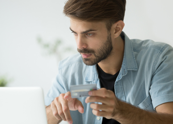 Man entering credit card information on a laptop for online food delivery.