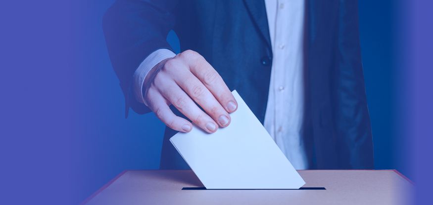 Person in a suit casting a ballot in an election box.